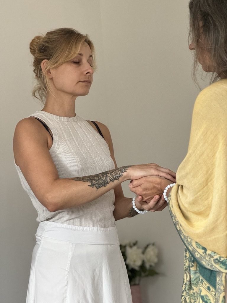 Zwei Frauen stehen sich gegenüber, Hände ineinandergelegt